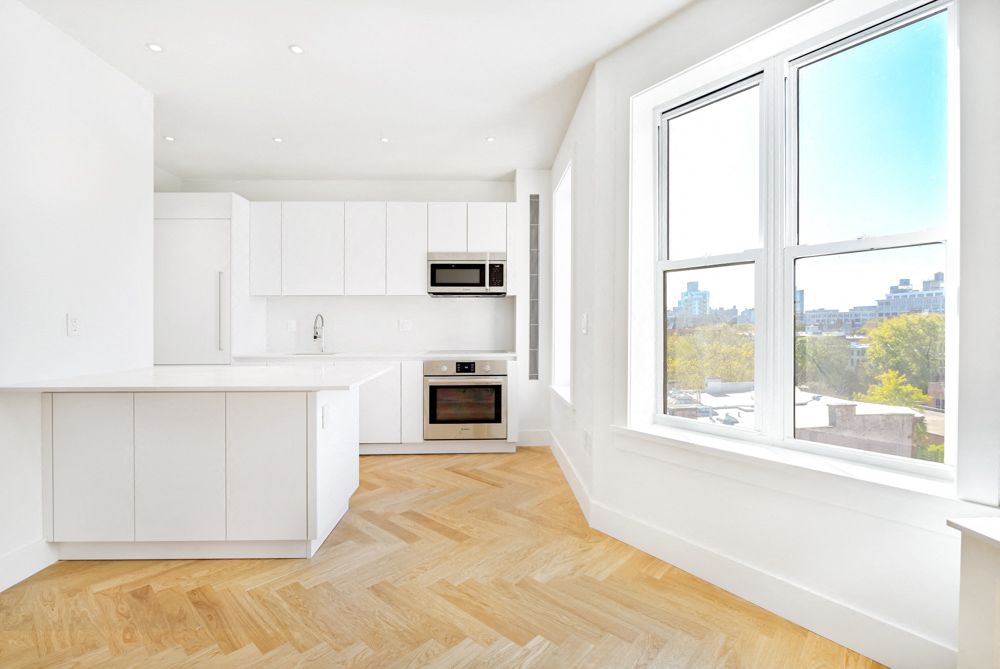 A kitchen with white cabinets and a wooden floor.